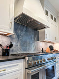 Modern kitchen with stainless steel stove, white cabinetry, and grey stone backsplash. Enhanced by ProlineRangeHoods.com PLJL Hurricane Range Hood Insert/Liner with 600/1200 CFM.