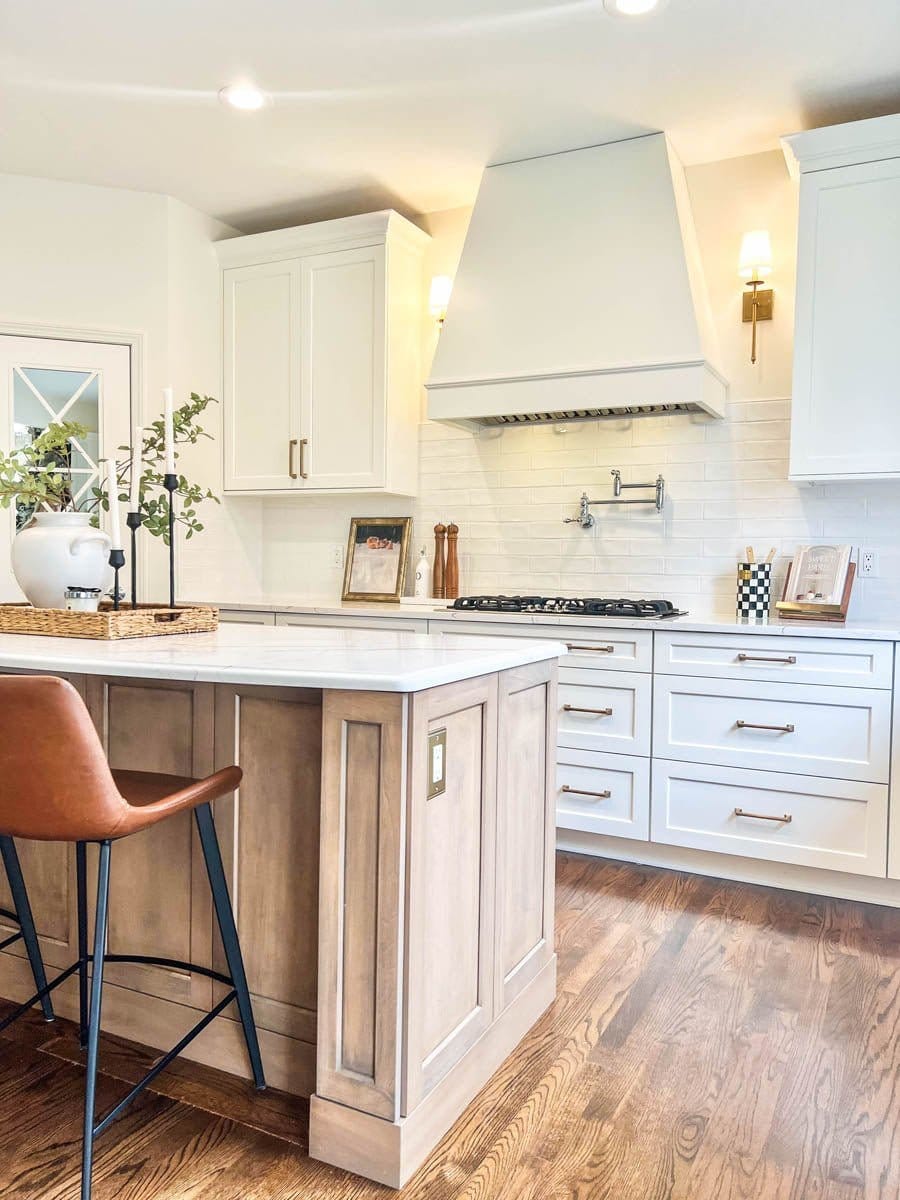 A contemporary kitchen with white cabinets, stainless steel appliances & ProlineRangeHoods.com featuring a PLJL INS Hood.