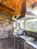 Outdoor kitchen with ProlineRangeHoods.com Island Range Hood, stainless finish, LCD controls, stone wall, wood ceiling.