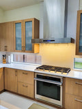 Modern kitchen with a stainless stove, oven, ProlineRangeHoods.com Wall Mounted Range Hood (1100 CFM), wood cabinets, white countertop.