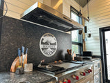 A modern kitchen with stainless appliances, a ProlineRangeHoods.com 1800 CFM hood, state-of-the-art stove, and "BOUNO'S" logo.