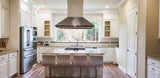 Modern kitchen with white cabinets, a large island, and ProlineRangeHoods.com PLJI 109 Hood, offering 1200 CFM power.