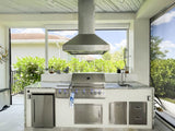 An outdoor kitchen featuring ProlineRangeHoods.com PLJI 103 Island Hood with 1200 CFM, robust cabinets, and verdant greenery.