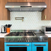 Modern kitchen with blue oven, gas stove, ProlineRangeHoods.com range hood, utensils, kettle, and toaster oven.