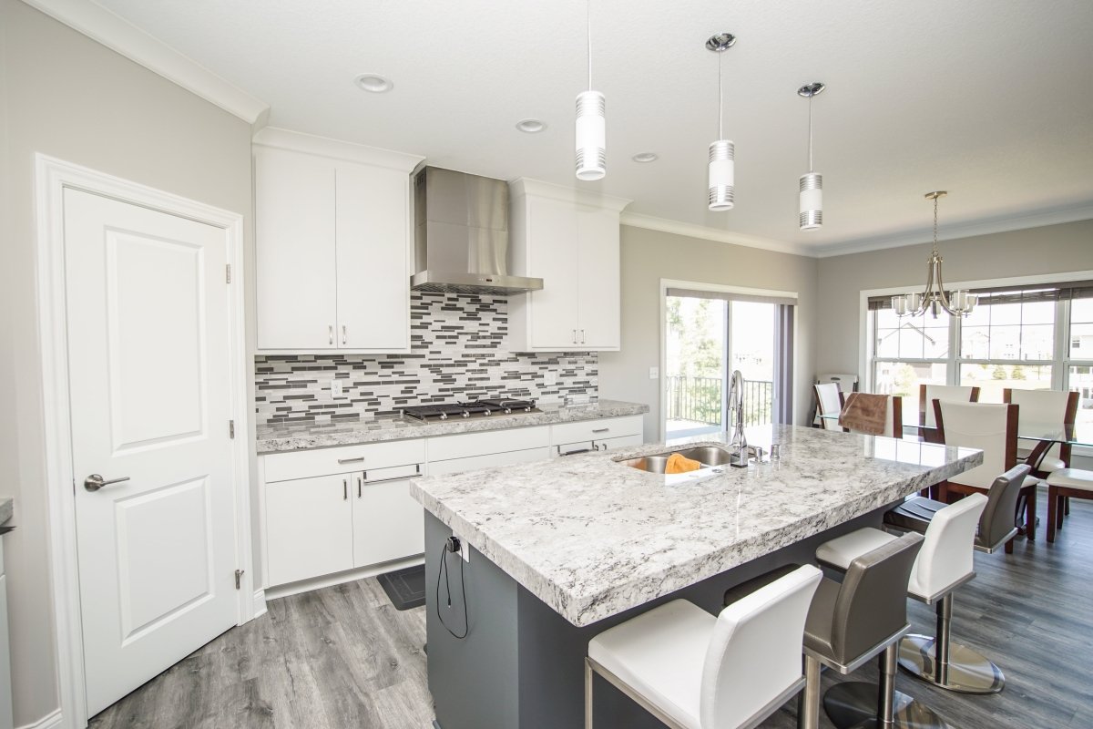 Contemporary kitchen with white cabinets, marble island, and ProlineRangeHoods.com Proline PLFW 750 Hood in stainless steel.