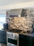 Modern kitchen with gas stove, ProlineRangeHoods.com PLJW 102 range hood, and black-and-white tile backsplash.