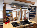 Cozy kitchen with a spiral staircase, decorated with holiday figurines. Effective ventilation by ProlineRangeHoods.com 900 CFM hood. TV shows a scenic view.