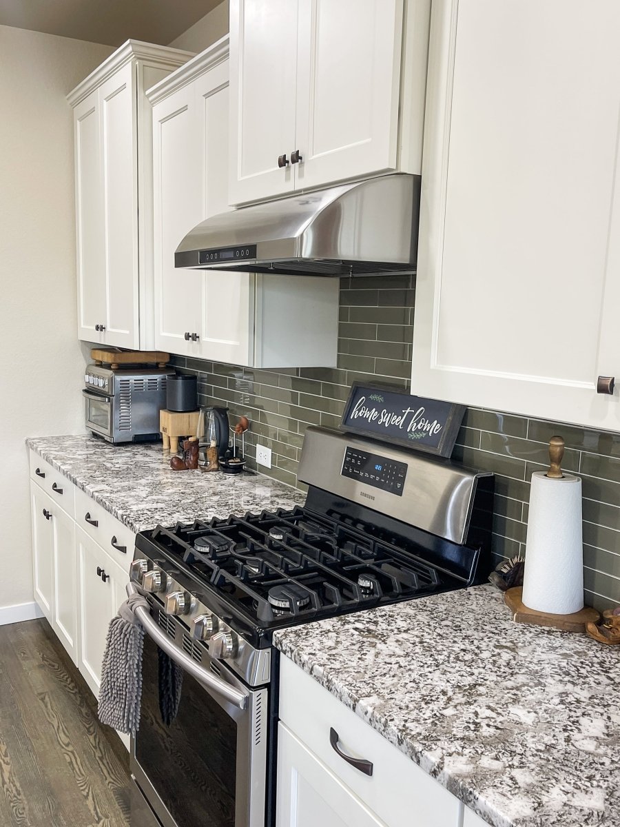 Modern kitchen with white cabinets, granite counters, a stainless stove & ProlineRangeHoods.com 900 CFM under-cabinet hood.