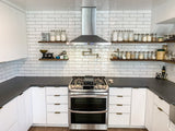 A modern kitchen with white cabinets, subway tiles, and a ProlineRangeHoods.com PLFW 520 Range Hood offers style and freshness.