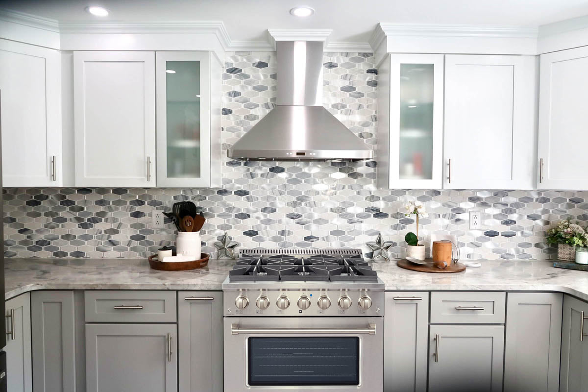A modern kitchen featuring ProlineRangeHoods.com's PLSR gas range in stainless steel, with white cabinets.
