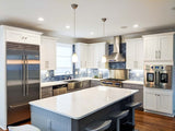 Modern kitchen with white cabinets, ProlineRangeHoods.com PLJW 130 wall-mounted hood, 900/1200 CFM, island, LCD controls.