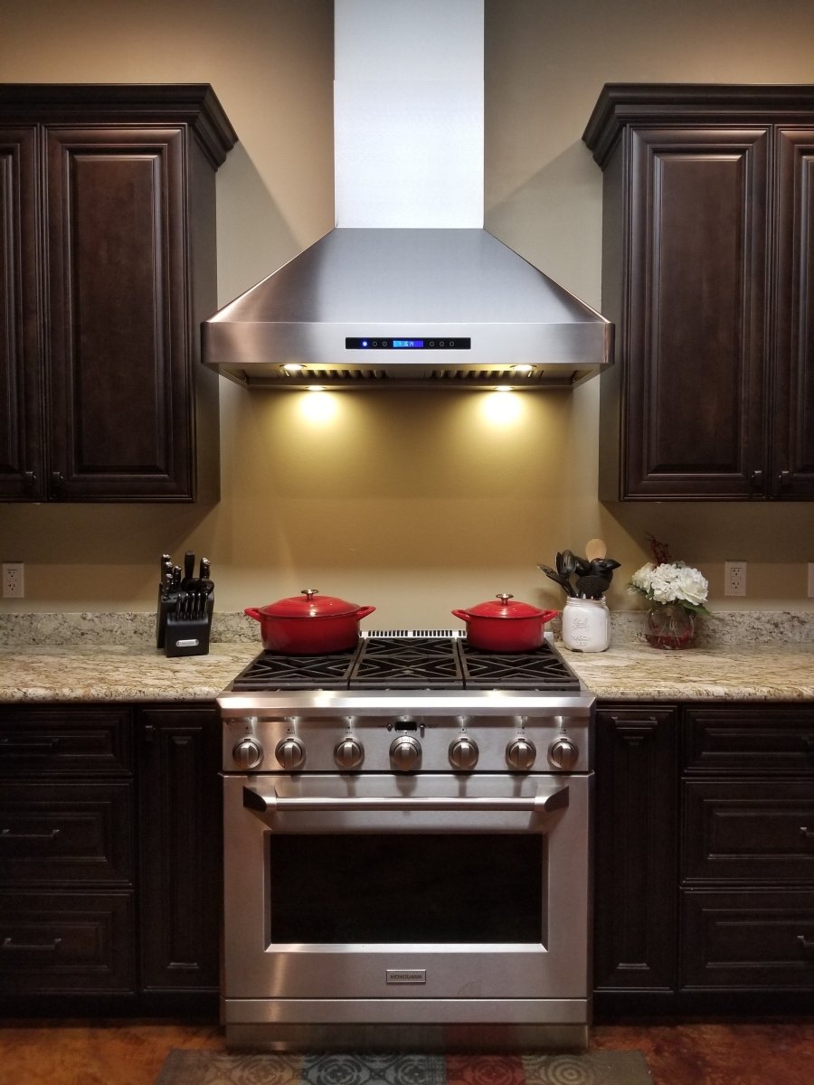 A modern kitchen featuring a stainless steel stove, dark cabinets, and the Proline PLJW 130 Hood from ProlineRangeHoods.com.