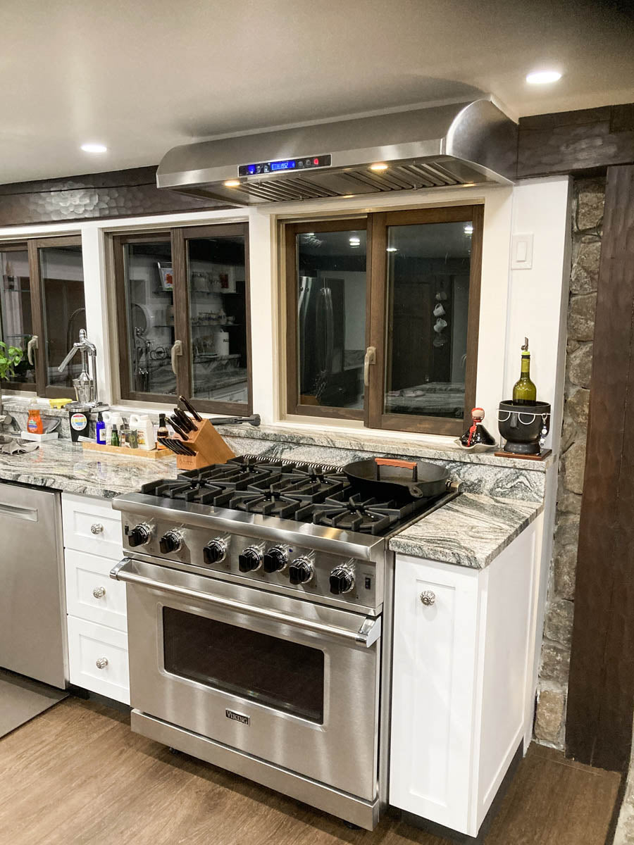 Modern kitchen with gas stove, granite counters, window, and Proline PLJW 117 Range Hood from ProlineRangeHoods.com.
