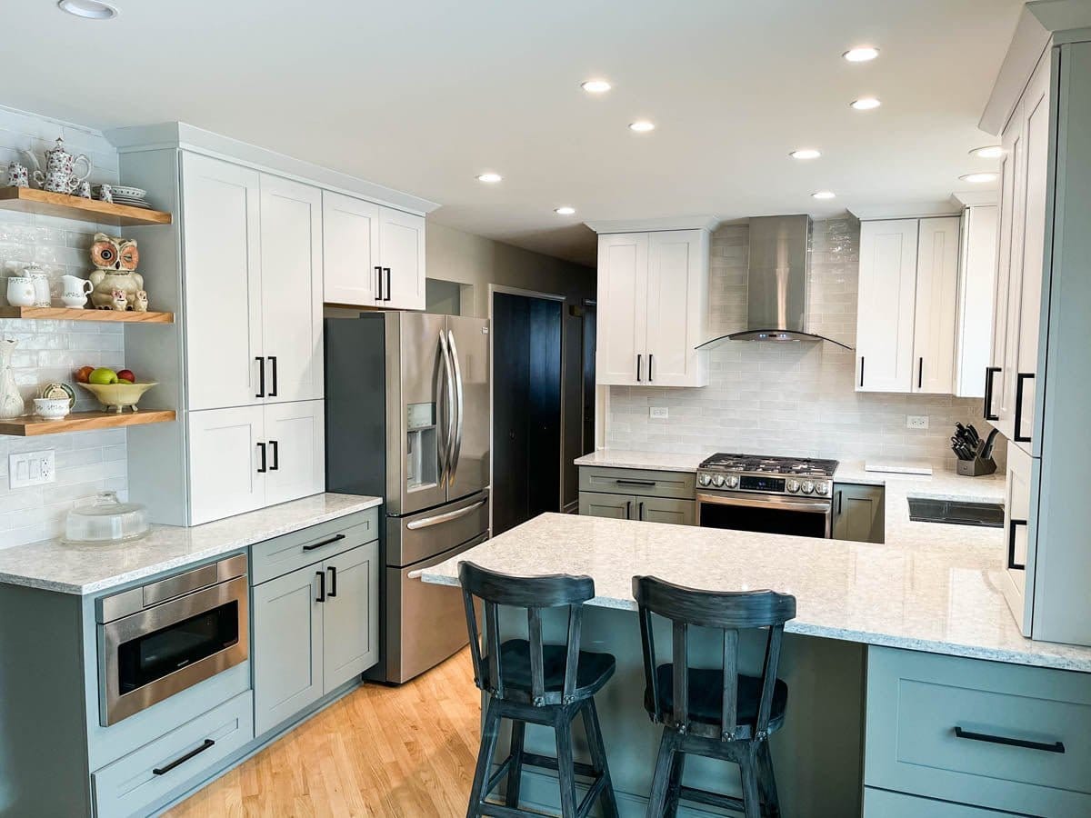 Modern kitchen with white cabinets, stainless appliances, island seating, and ProlineRangeHoods.com’s PLFW 544.