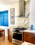 Modern kitchen with marble, wood, art, blue vase, ProlineRangeHoods.com PLFW 544 quiet stainless range hood.
