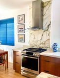 Modern kitchen with marble, wood, art, blue vase, ProlineRangeHoods.com PLFW 544 quiet stainless range hood.
