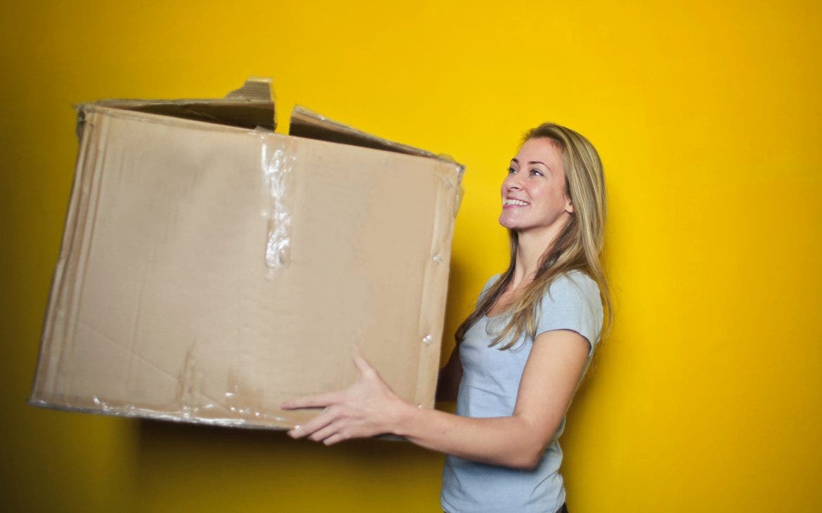 woman in grey shirt holding brown cardboard box 761999