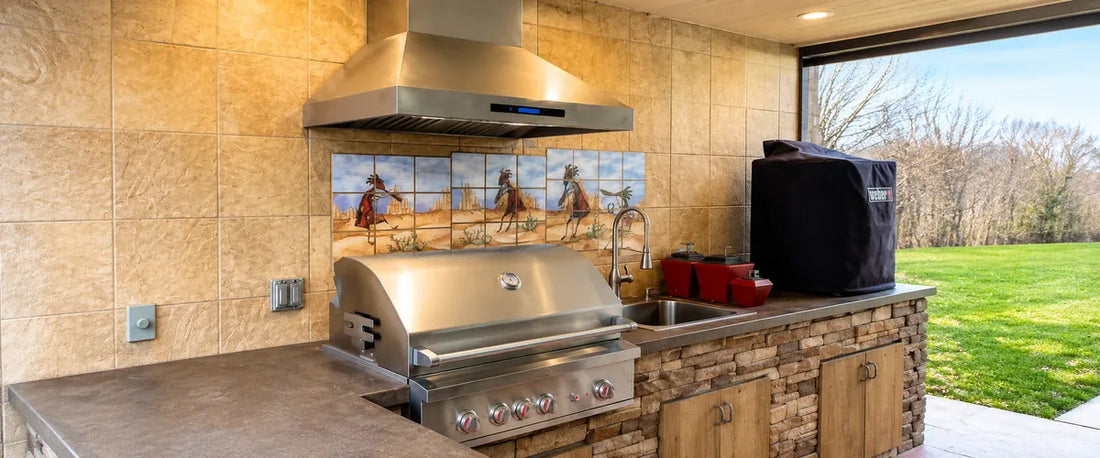 Outdoor kitchen with a stainless steel range hood installed above a built-in grill