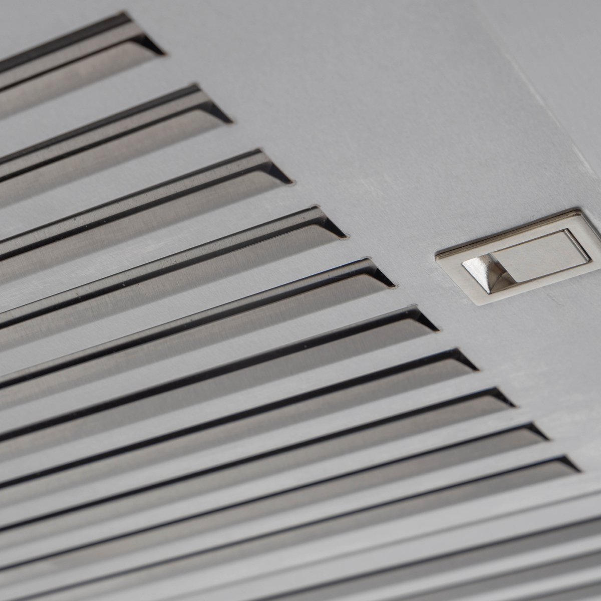 Close-up of ProlineRangeHoods.com PLJW 129 wall-mounted hood with narrow slats & button, offering premium airflow.