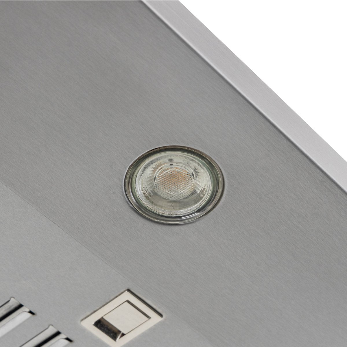 Close-up view of a round light in a metallic surface with a square button, part of the Proline PLJW 129 Range Hood on ProlineRangeHoods.com.