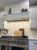 White kitchen featuring a stainless stove, ProlineRangeHoods.com Insert Range Hood (model PLFL 832), wooden cutting board, and pumpkins.