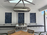 Outdoor kitchen with ProlineRangeHoods.com vent hood for BBQ, 2000 CFM, 304 steel, herringbone backsplash & wood table.