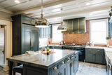 A modern kitchen with dark green cabinets, marble island, and stainless steel appliances from ProlineRangeHoods.com features the Proline PLFL 832, a 54-60-inch Insert Range Hood offering consistent ventilation performance at 1000 CFM.