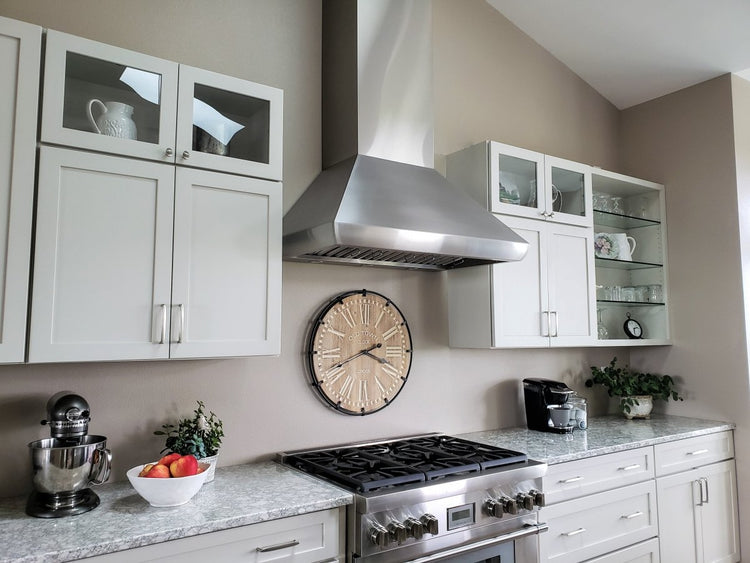 Modern kitchen with stainless steel stove, large white cabinets, and a decorative clock. ProlineRangeHoods.com elevates the space.