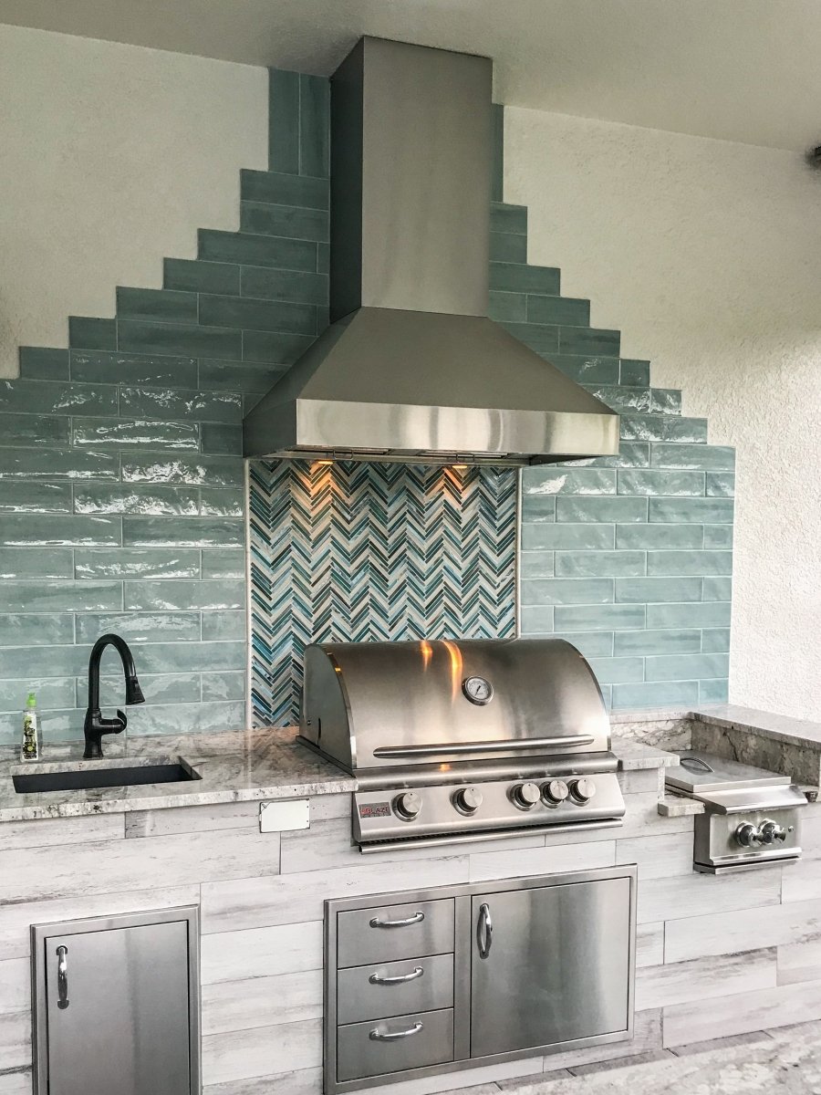 Outdoor kitchen with stainless steel grill, turquoise backsplash, sink, and ProlineRangeHoods.com 54" & 60" Wall Range Hood - ProV 60WC.