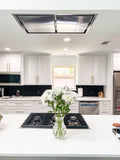 Modern kitchen with white cabinets, black backsplash, and Proline 42" ceiling range hood. ProlineRangeHoods.com.