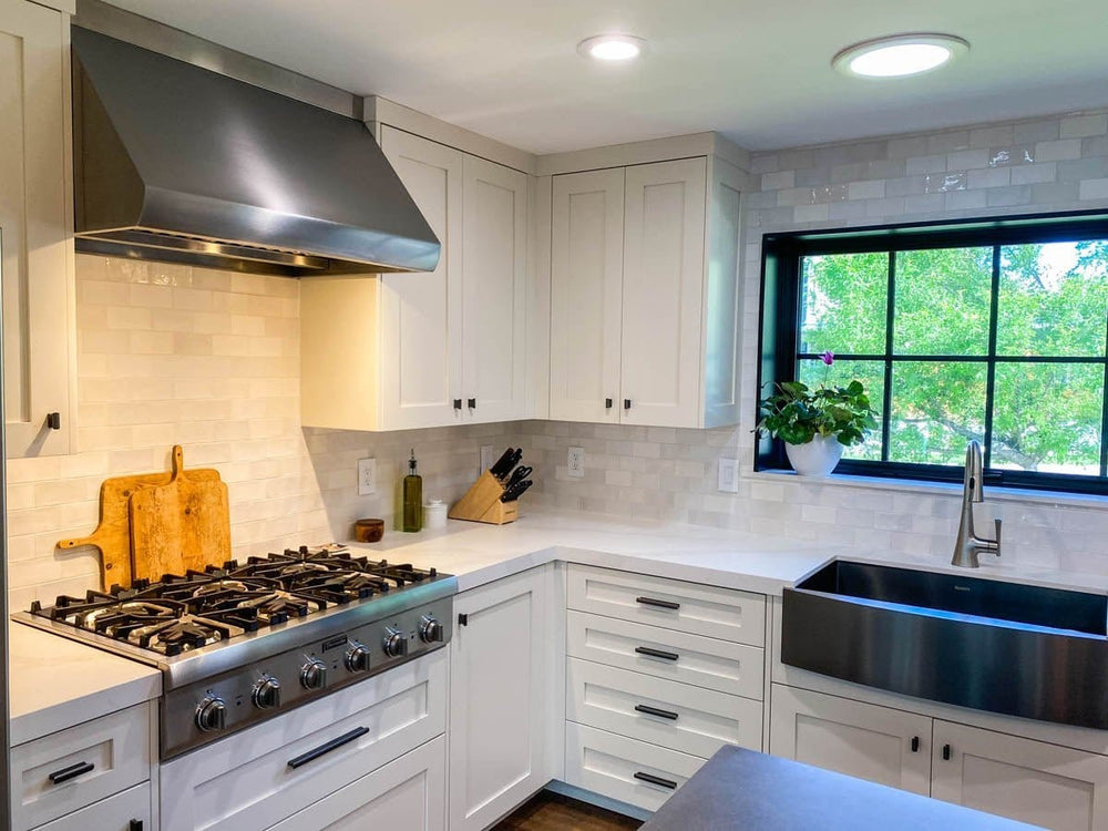 Modern kitchen with white cabinets, stainless stove, farmhouse sink, Proline PLJW 109 hood. ProlineRangeHoods.com.
