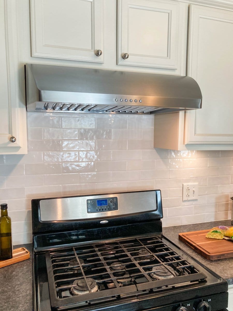 A modern kitchen features a ProlineRangeHoods.com PLJW 133 hood, 900 CFM, ductless with white cabinets and subway tiles.
