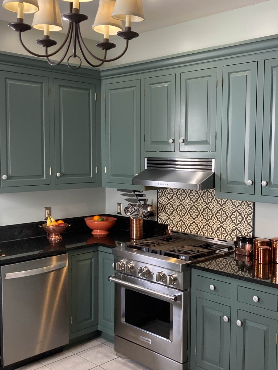 A modern kitchen with green cabinets, stainless appliances, decorative tile backsplash, chandelier, and ProlineRangeHoods.com Recirculating Kit for efficient ventilation.