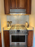 A modern kitchen stove, stainless steel oven, wooden cabinets, utensils on the counter, and a ProlineRangeHoods.com recirculating kit for efficient ventilation.