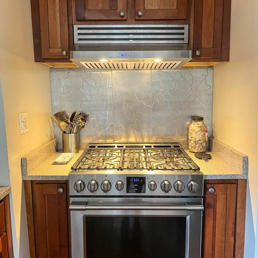 Modern kitchen stove with utensils, a jar, and Proline 48" Recirculating Kit range hood above. ProlineRangeHoods.com.